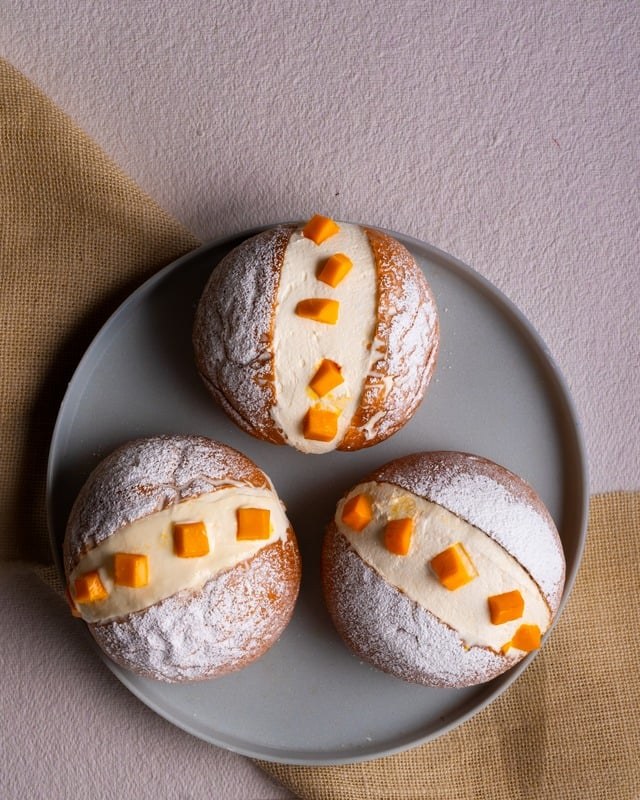 Three powdered white sweets arranged on a grey plate