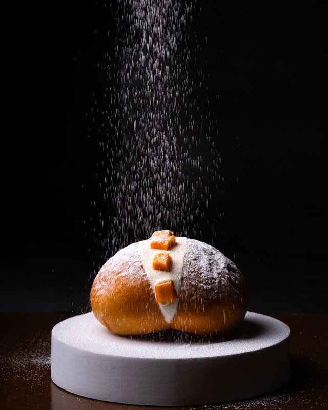Single pastry on a white plate under a dusting of powdered sugar