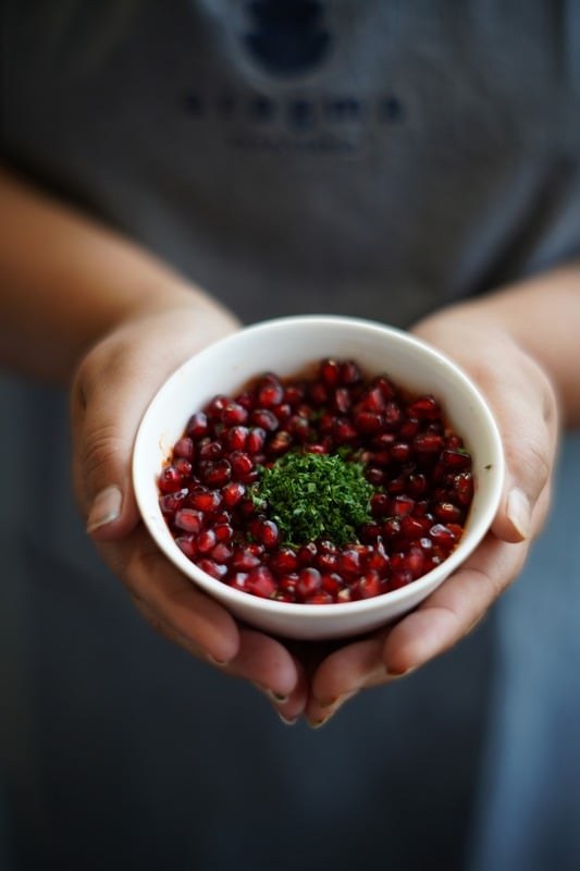 Hands holding a bowl of red ingredients during food preparation